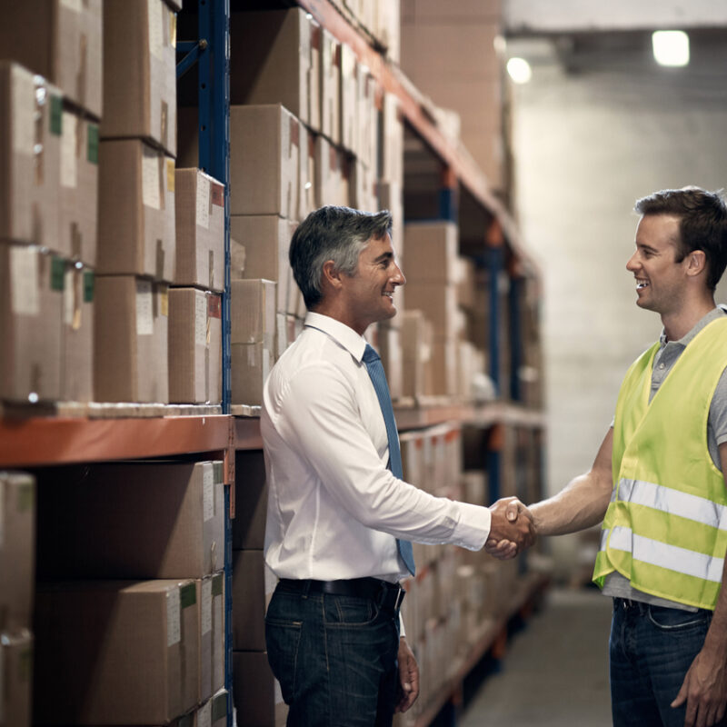 Shot of two men shaking hands in a large warehouse