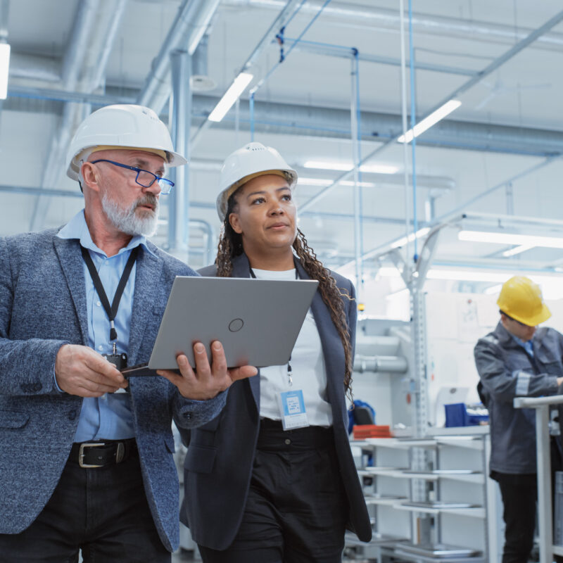 Two Professional Heavy Industry Engineers Wearing Hard Hats at Factory.